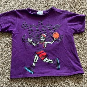 This shirt is beautiful with a dark shade of purple with a skeleton playing:).